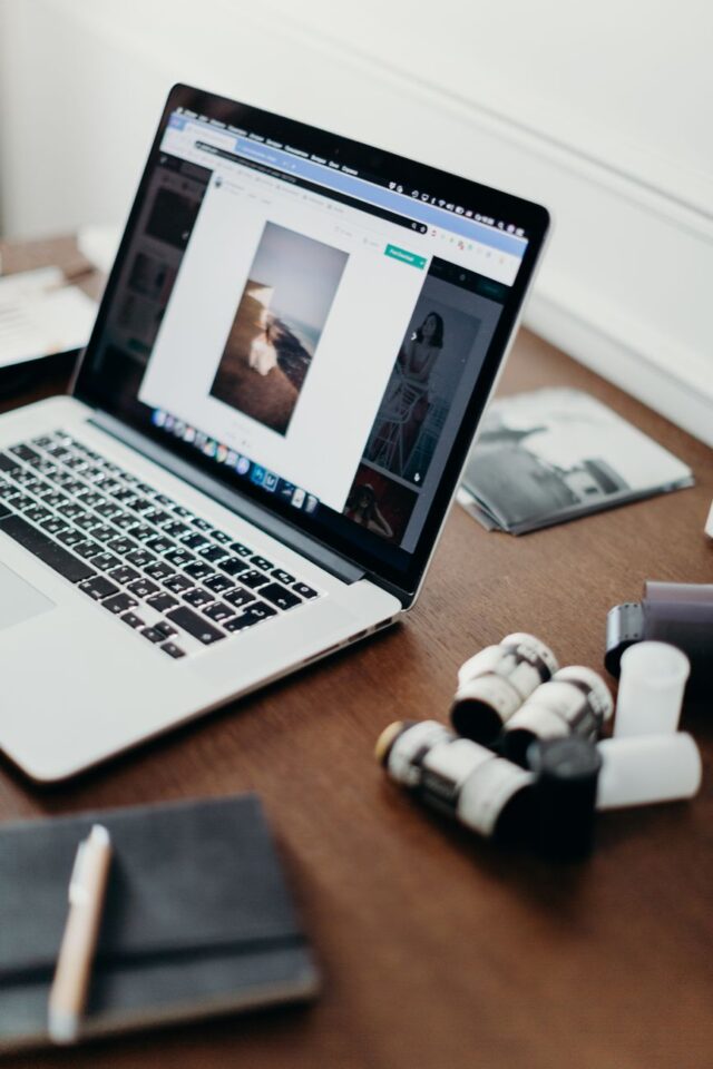 Gros plan d'un ordinateur portable sur un bureau avec des bobines de film, mettant en avant le workflow de la photographie.